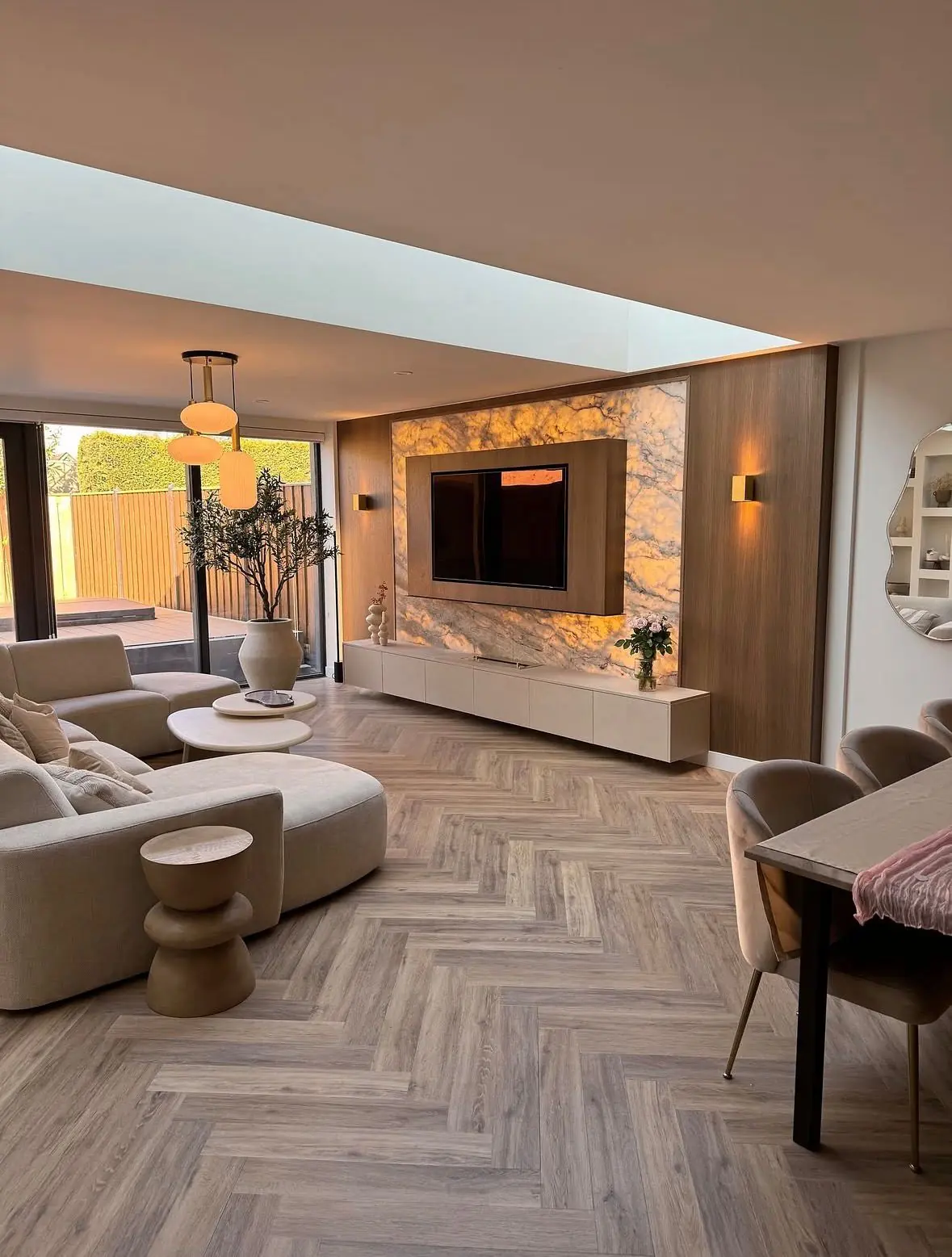 Open-plan living room with herringbone flooring, a marble feature wall and a cream curved sofa