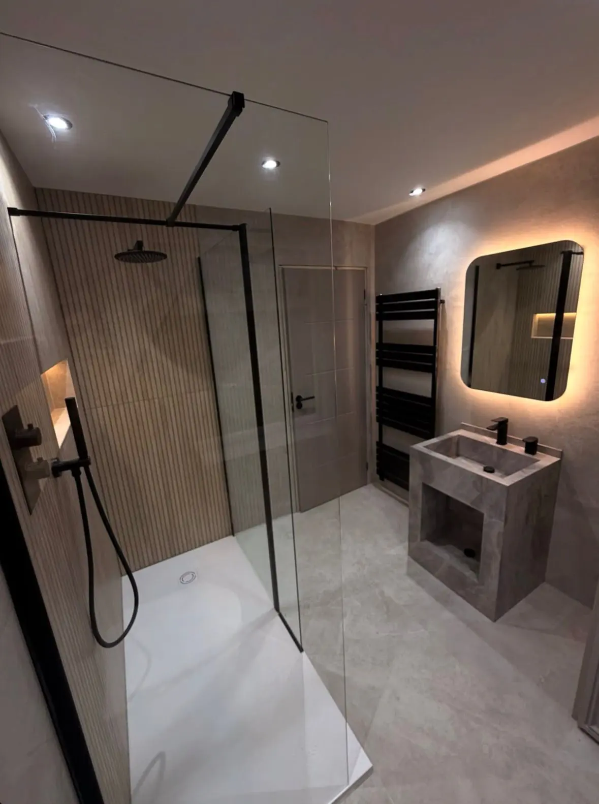 Bathroom with a walk-in shower, a stone basin and a backlit mirror